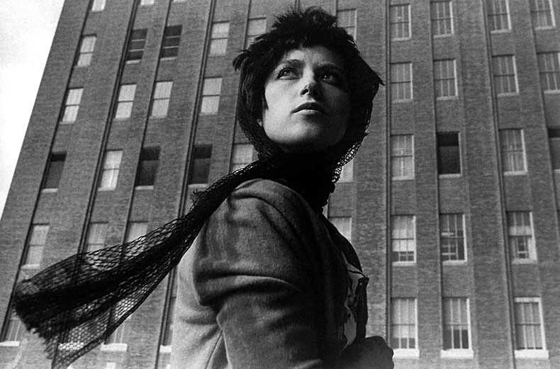 Schwarz-weiß-Foto einer Frau mit wehendem Schal vor Hochhaus