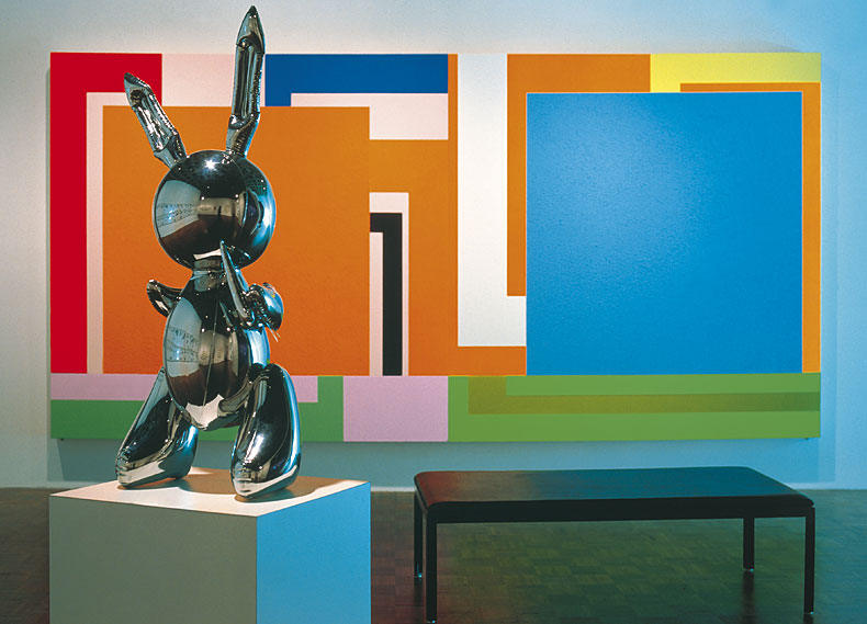 glänzende Skulptur einer Hasenfigur vor einem Bild mit großen bunten Flächen