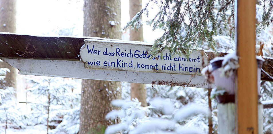 Schild mit religiöser Inschrift in verschneitem Wald