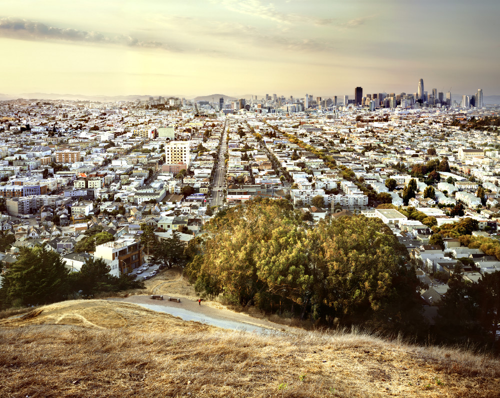 Blick aus der Vogelperspektive über eine Stadt mit Hochhäusern und Bergen im Hintergrund