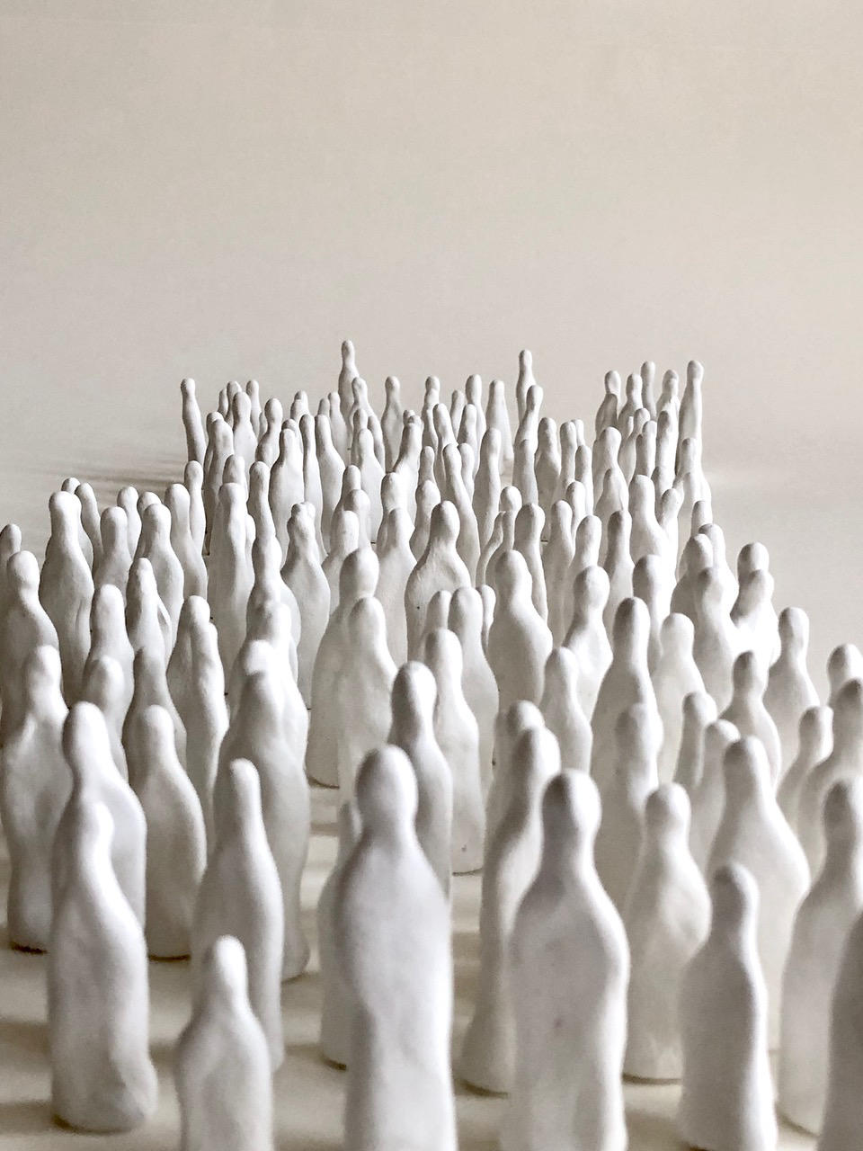 eine große Gruppe weißer, abstrakter
            Miniaturfiguren auf hellem Untergrund